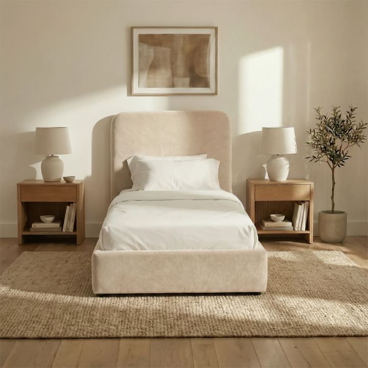 [Single | Beige] Front view of Pluva ottoman bed with curved headboard centred between matching nightstands and table lamps