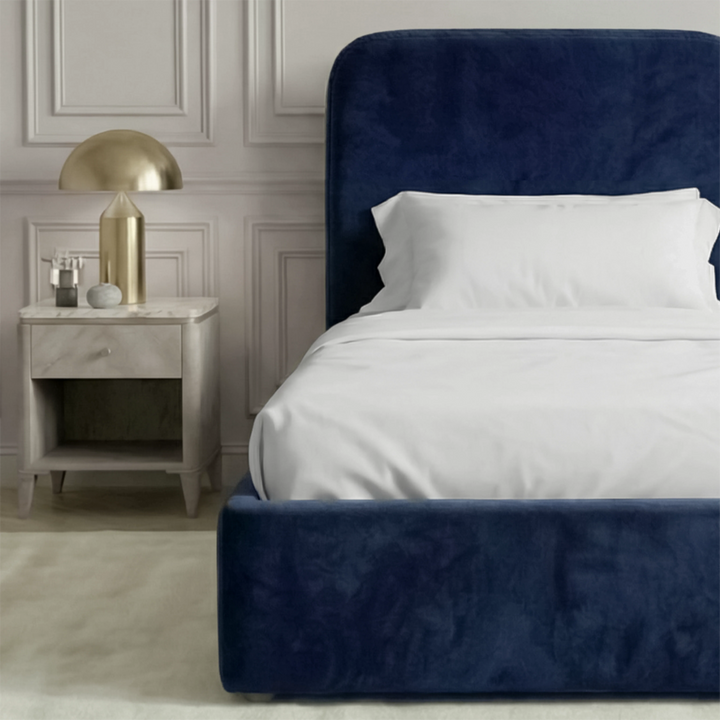 [Single | Blue] Side angle of Pluva ottoman bed showing curved headboard profile and clean velvet base beside nightstand