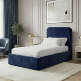 [Single | Blue] Velvet Pluva bed in bedroom with olive tree in vase, brass nightstand lamp and upholstered armchair