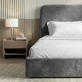 [Single | Grey] Side angle of Pluva ottoman bed showing curved headboard profile and clean velvet base beside nightstand
