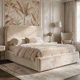 [King | Beige] Pluva ottoman bed with curved padded headboard dressed in cream bedding beside wingback chair and brass lamp