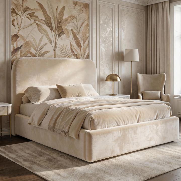 [King | Beige] Pluva ottoman bed with curved padded headboard dressed in cream bedding beside wingback chair and brass lamp