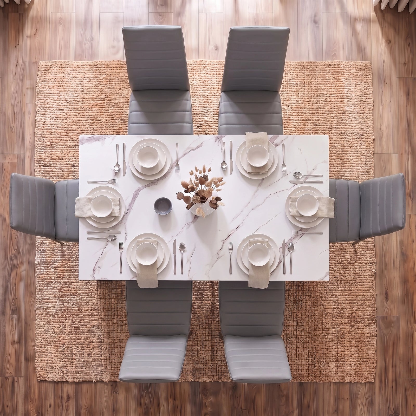 [6 Seater | Grey] Overhead view of a modern dining set featuring a rectangular white marble-patterned table surrounded by six gray upholstered chairs, set on a woven jute rug over a wood floor.