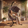 [Grey] A girl taking sunbath in a round light grey hanging egg chair with cushions, pillows and a throw for cozy seating.