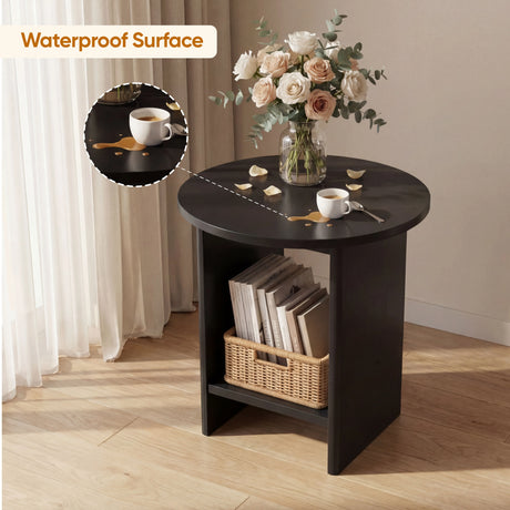 [Black] Round black side table styled with roses; lower shelf holds stacked books beside woven basket