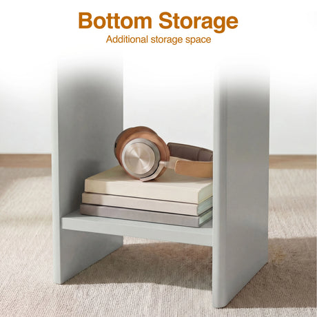 [Grey] Bottom storage shelf of grey round side table holding brown headphones on two stacked books