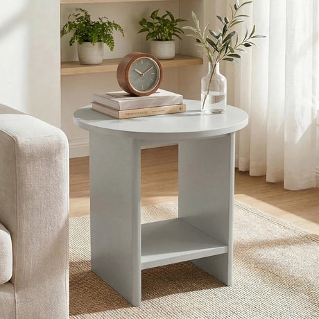 [Grey] Small round side table on woven rug with table clock and stacked books on rounded top