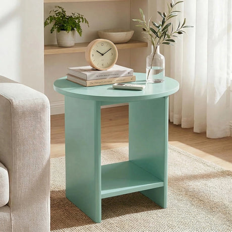 [Sage Green] Small round side table on woven rug with table clock and stacked books on rounded top