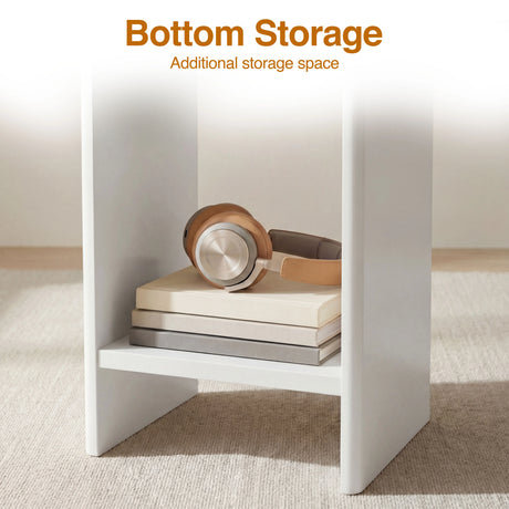 [White] Bottom storage shelf of white round side table holding brown headphones over two stacked books