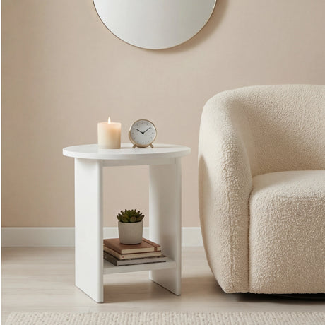 [White] Round white end table styled in living room with pillar candle, silver clock and potted plant on shelf
