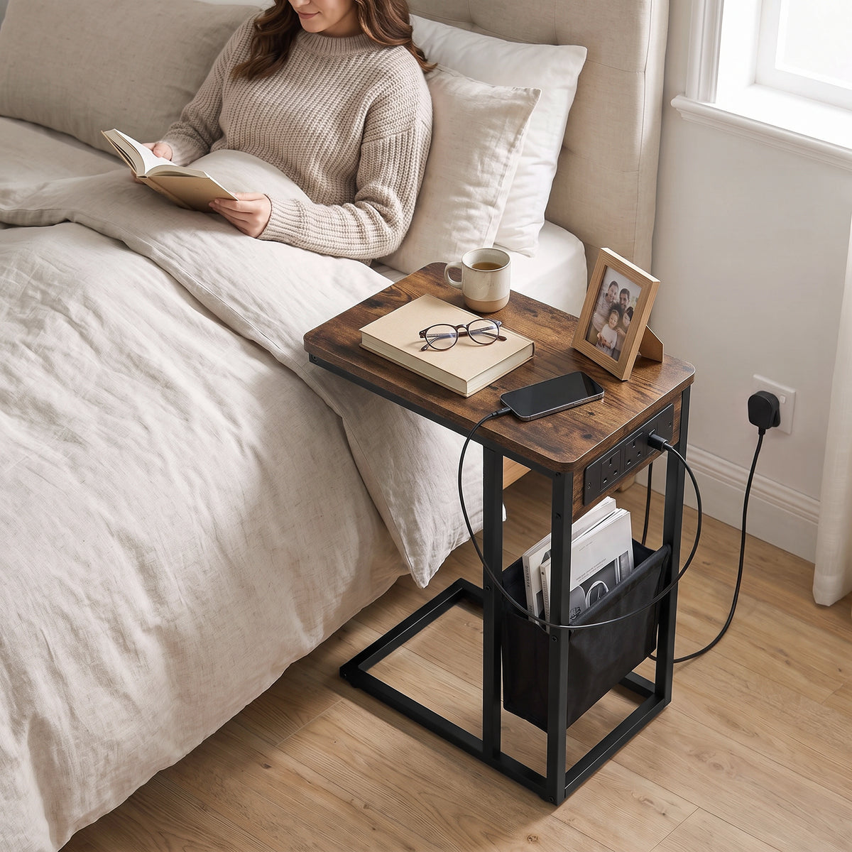 [Rustic] side table beside bed with rustic wood-effect top, charging station, lamp, phone and storage pouch