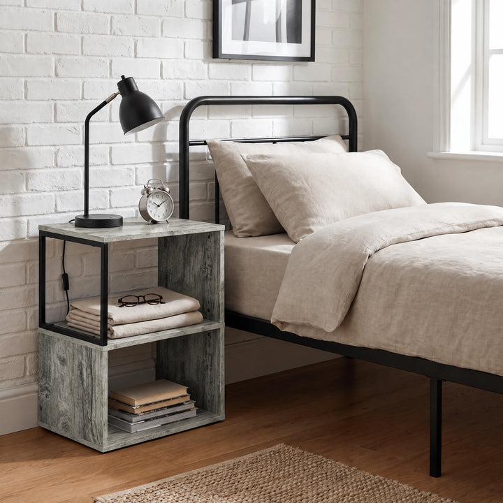 [Rustic Grey] This narrow side table stands beside a bed with a lamp, folded bedding and books on its open shelves.