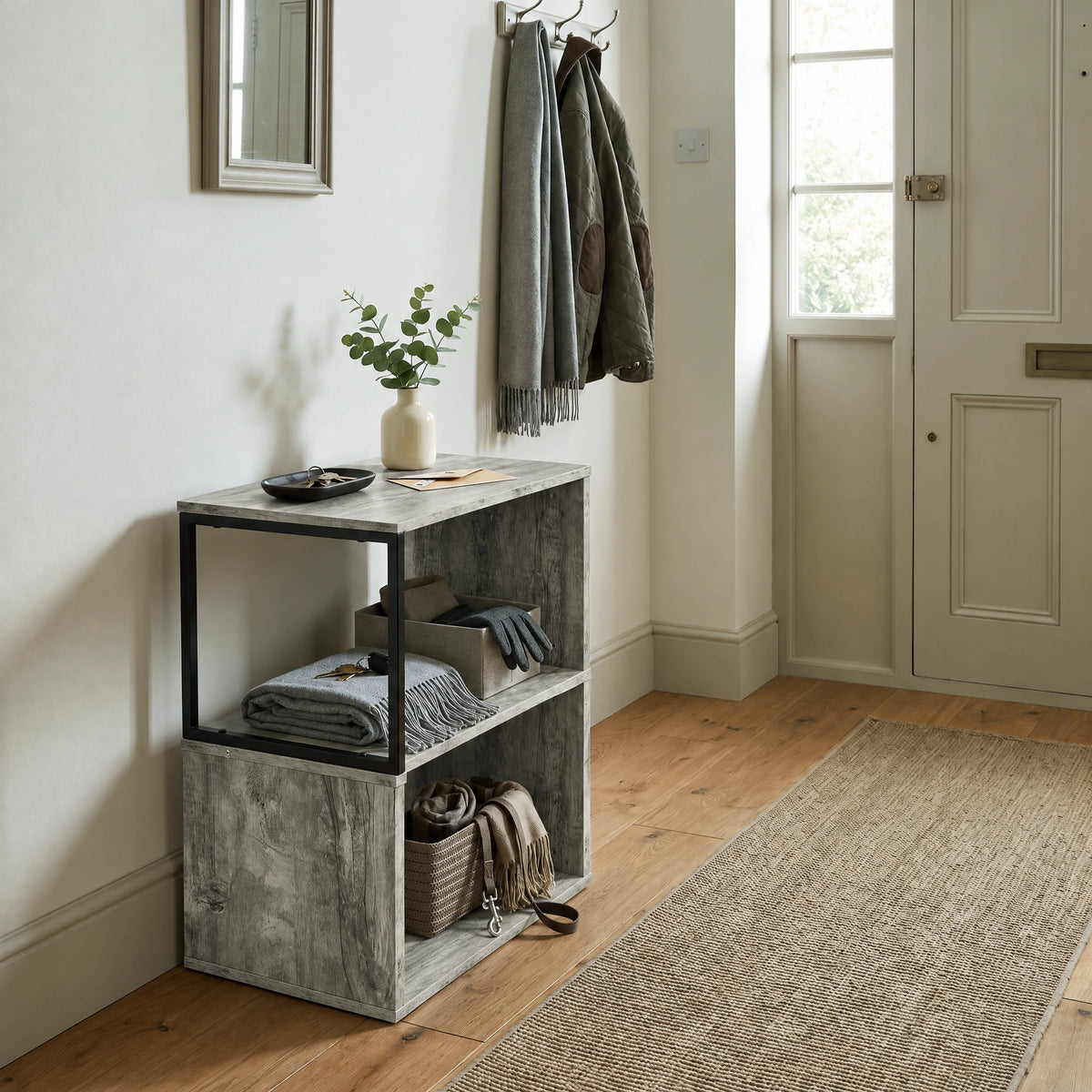 [Rustic Grey] This narrow side table stands in a hallway with a plant, folded textiles and accessories on its open shelves.