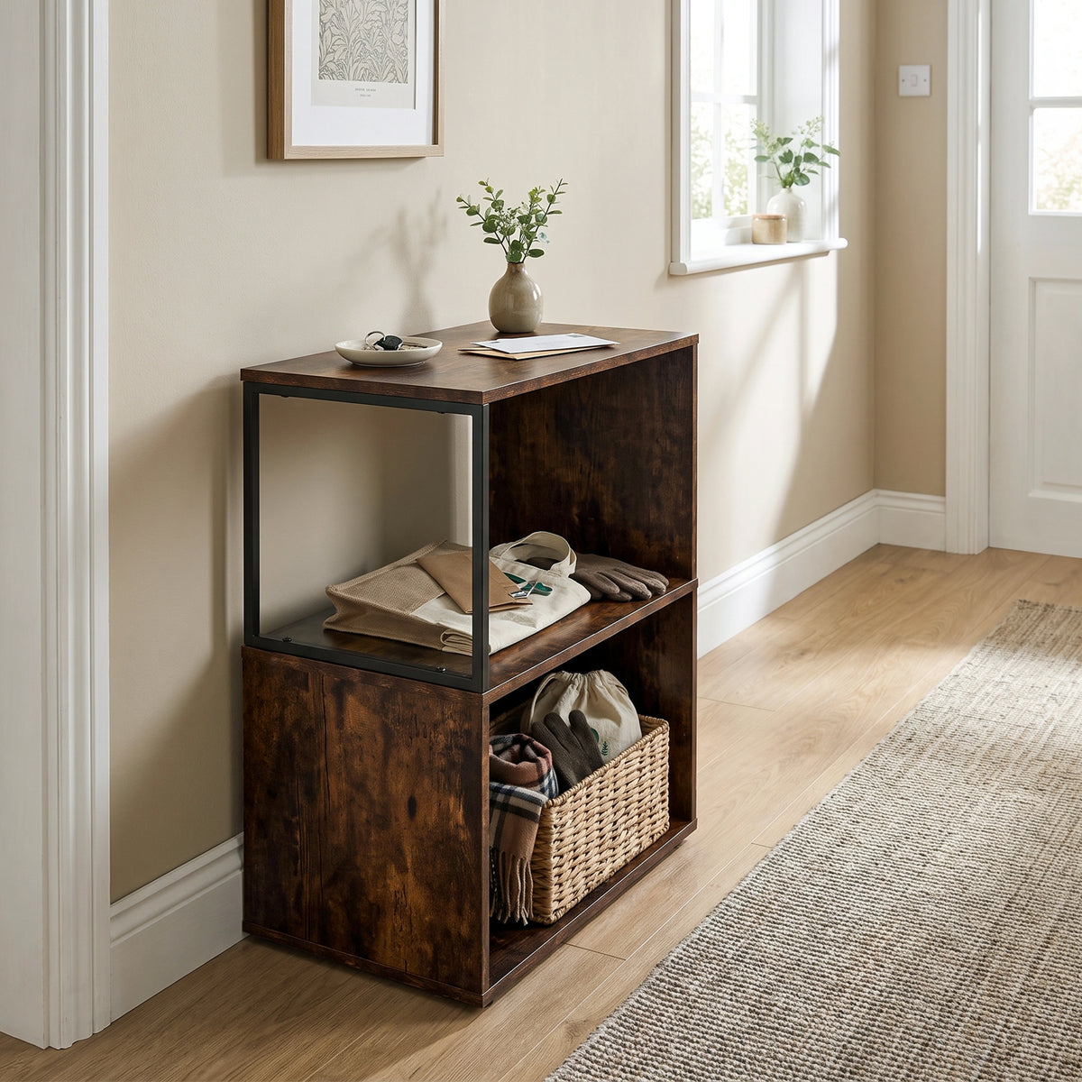 [Rustic] This narrow side table stands in a hallway with a vase, folded textiles and a basket on its open shelves.