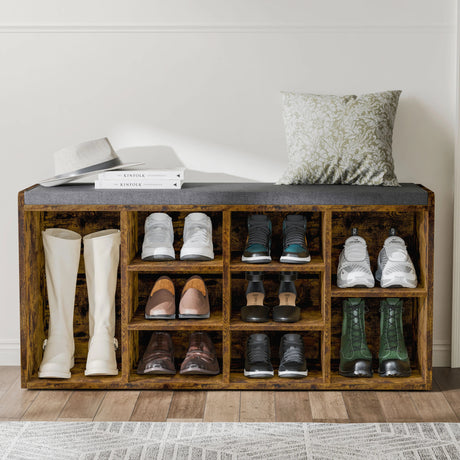 Hallway shoe storage bench with cushion and adjustable shelves in rustic wood finish, holding various shoes and boots in entryway setting.