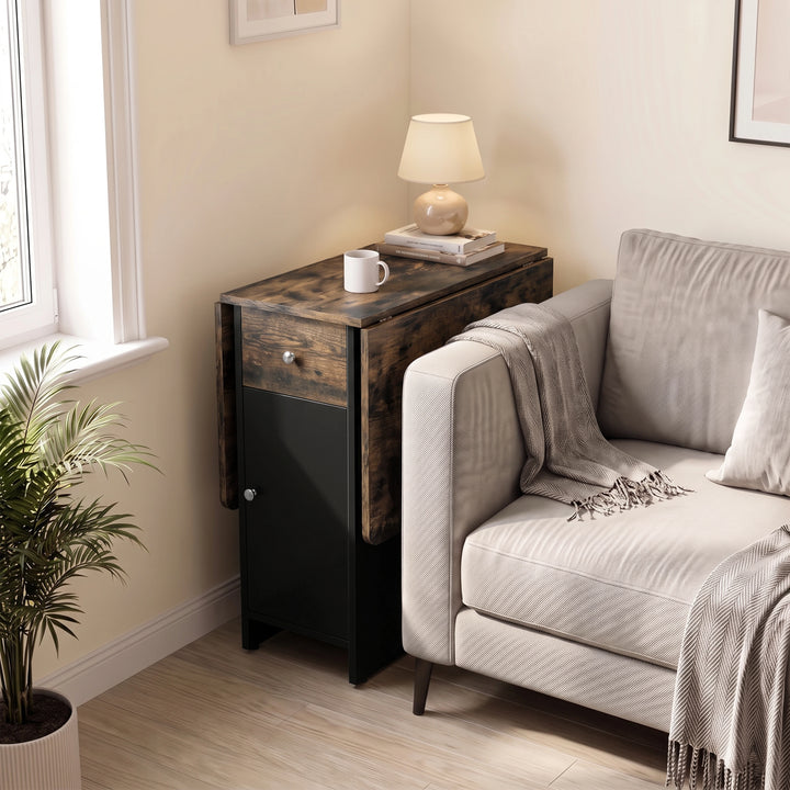 [Rustic] Small folding dining table closed beside a sofa featuring black cabinet with lamp, mug & books on wood-effect top.