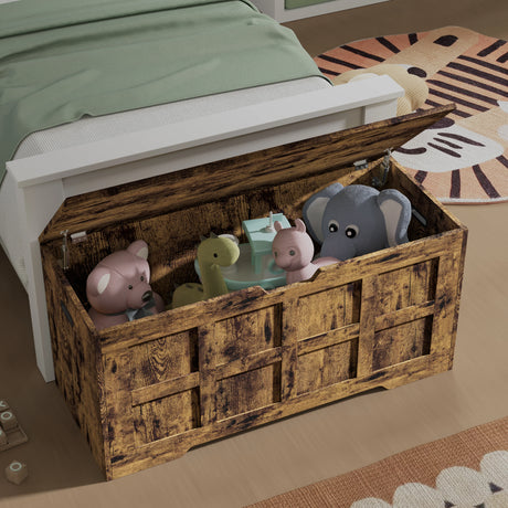 Wooden toy chest with children's toys inside, placed on a bed in a bedroom setting.