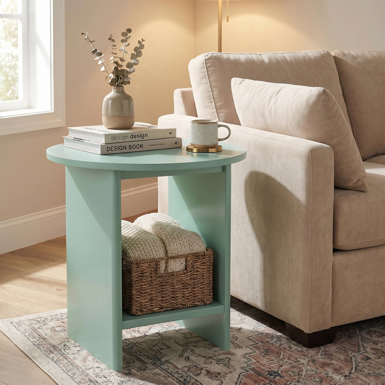 [Sage Green] Small Round Side Table with Shelf Living Room positioned beside a cream sofa with books and mug on top and wicker basket on lower shelf
