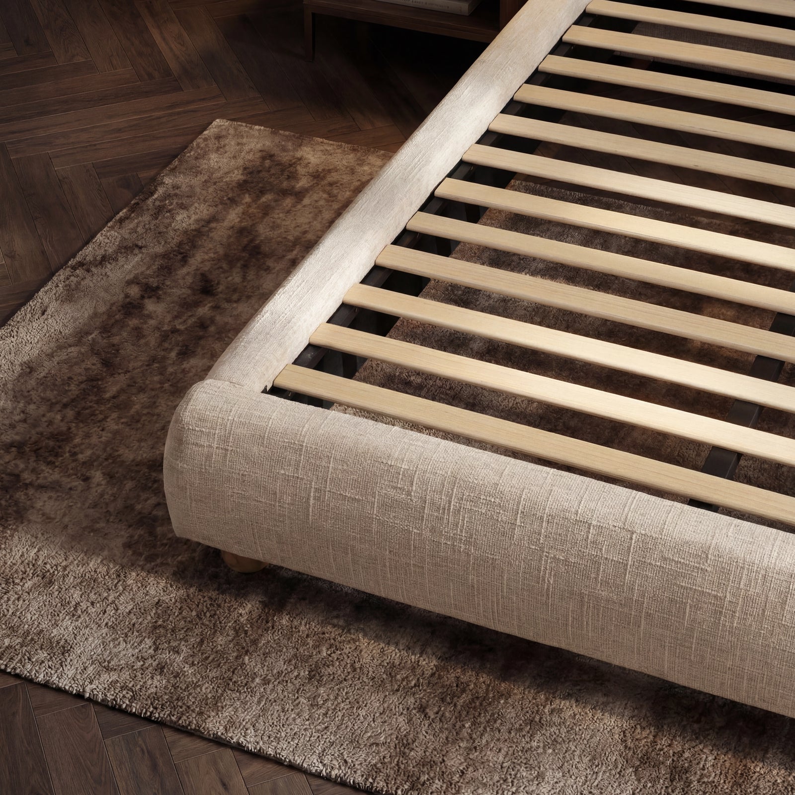 [King | Beige] Open slat support structure inside fabric bed frame with textured rug below