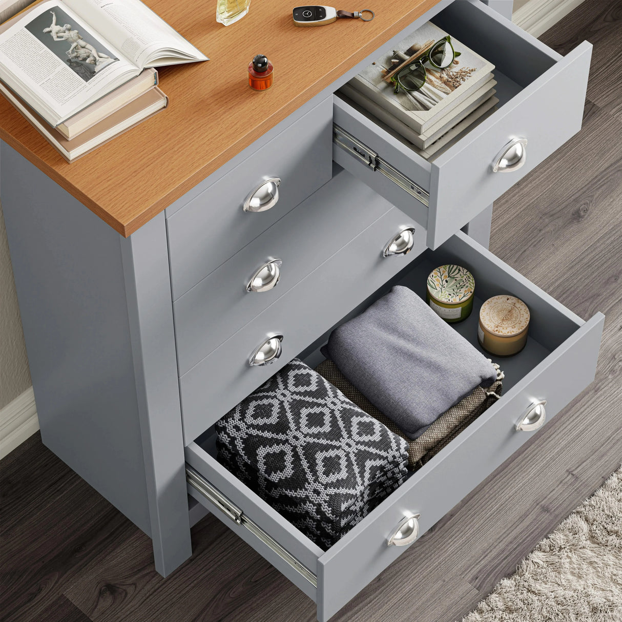[Grey] Chest of drawers interior view, metal runners visible with books and folded blanket