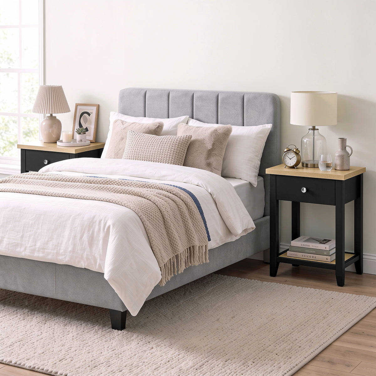 [Black] Wide bedroom scene showing the bedside table next to a bed with items on top and books below
