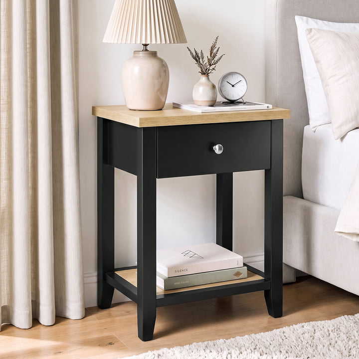 [Black] Angled bedroom view beside a bed with lamp, closed drawer and open lower shelf