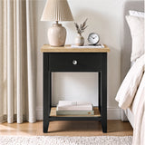 [Black] Bedside lifestyle view with lamp and clock on top, closed drawer and lower shelf