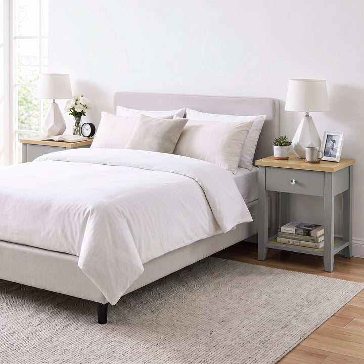 [Grey] Wide bedroom scene showing the bedside table next to a bed with books on the lower shelf