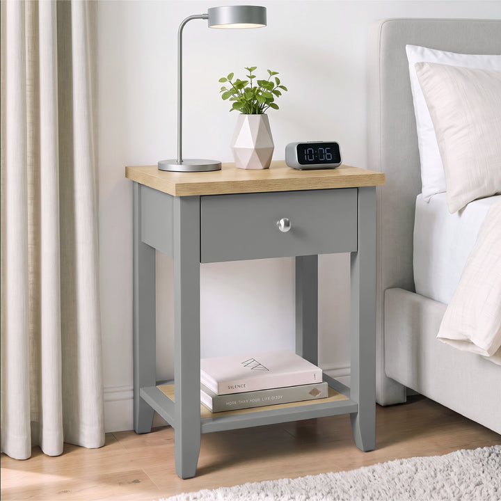 [Grey] Angled bedroom view beside a bed with desk lamp, closed drawer and open lower shelf