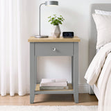 [Grey] Bedside lifestyle view with lamp, plant and clock on top, closed drawer and lower shelf