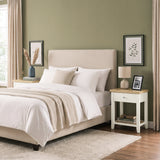 [White] Wide bedroom scene showing the bedside table next to a bed with books on the lower shelf