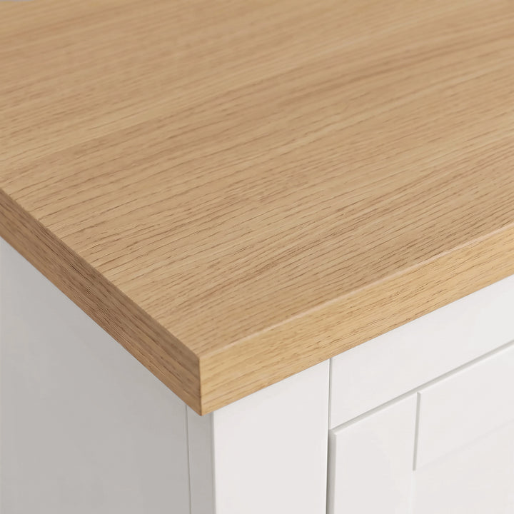 [White] Close-up shot of the natural light oak top corner and white painted finish on the Shaker Triple Wardrobe.
