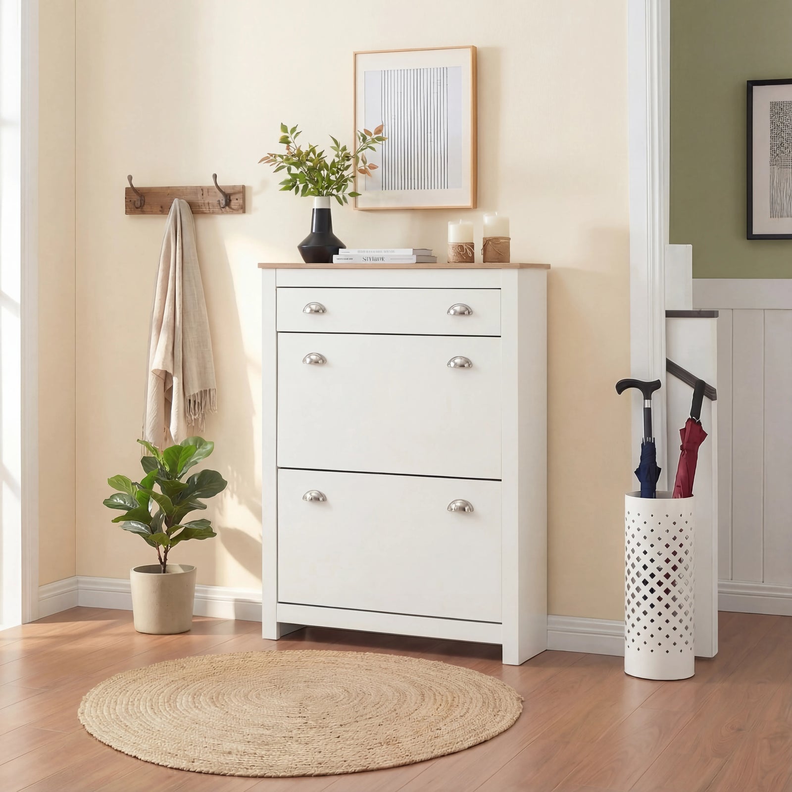 [White] White slim shoe cabinet closed front-on in hallway with framed art, coat hooks and umbrella stand