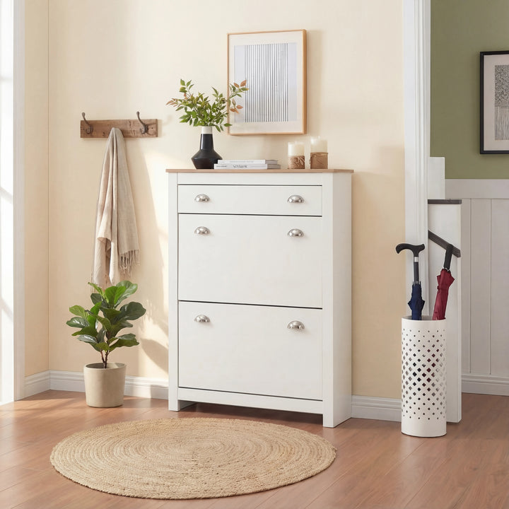 [White] White slim shoe cabinet closed front-on in hallway with framed art, coat hooks and umbrella stand