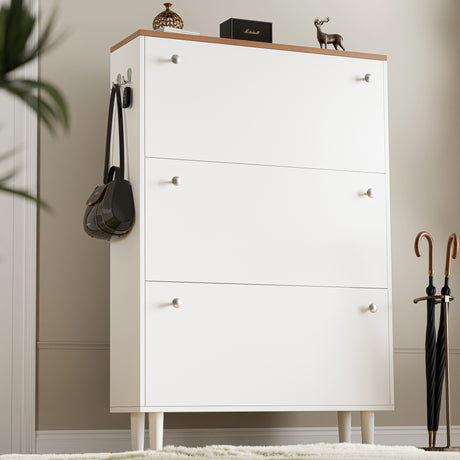 Tall three door shoe cabinet in white with oak top with two knobs on each pull out drawer, bag hanging on the side hook.