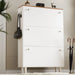 Tall three door shoe cabinet in white with oak top with two knobs on each pull out drawer, bag hanging on the side hook.