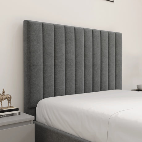 Gray upholstered headboard in a bedroom setting with a white bedspread.