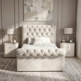 [Single | Beige] Front view of Chesterfield bed with tufted headboard, footboard, lamps, side tables, and wall art.