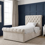[Single | Beige] Angled bedroom view showing tufted headboard, rolled footboard, window, lamp, and rug