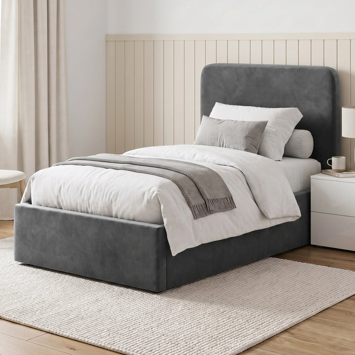 [Single | Grey] Straight front view with rounded headboard, footboard, pillows, bedside tables, lamps, and rug