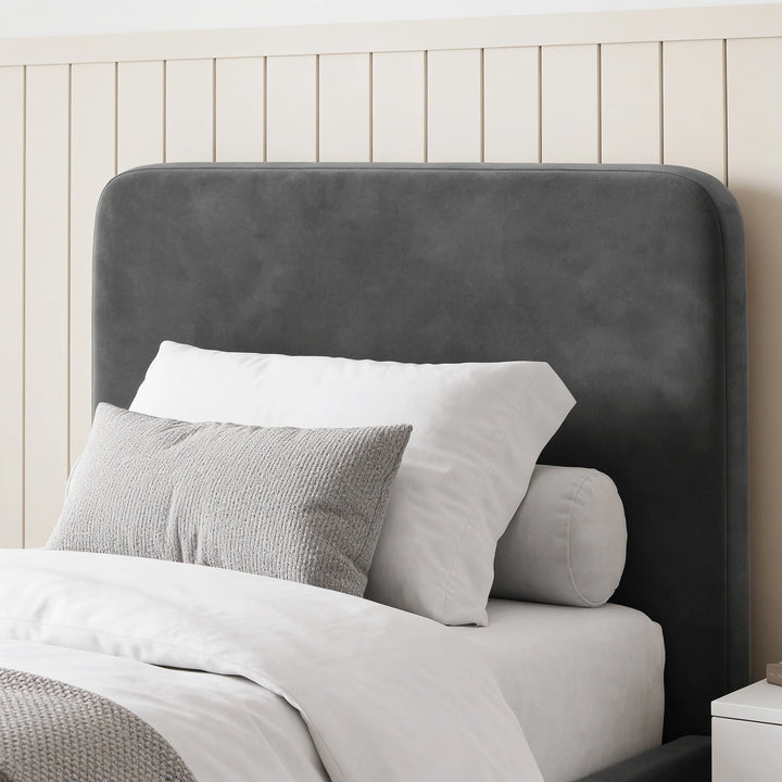 [Single | Grey] Close-up of rounded headboard with soft velvet texture, layered pillows, bolster, and panelled wall