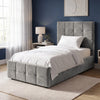 [Single | Grey] Angled bedroom view with square panel headboard, padded footboard, white bedding, lamp, and tall window