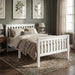 White single wooden bed frame with a slatted design, soft bedding, and decorative pillows in a cozy bedroom setting