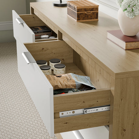Close-up of partially open Skova 6 chest of drawers in wooden white two-tone finish, showing jars and packaged items inside