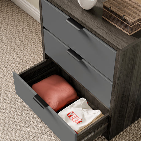 Wooden grey finish drawers for bedroom, with the lower drawer opened, showing folded clothing in a natural light space