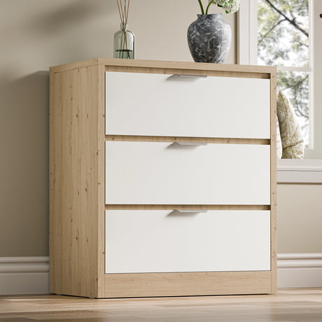 Skova three-drawer chest of drawers with a two-tone finish with decorative items on top, placed against a wall near a window