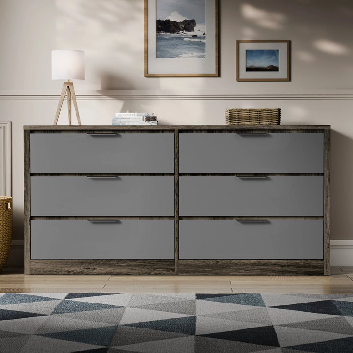 Two-tone finish wide chest of drawers placed in a bright room with a patterned rug and lamp