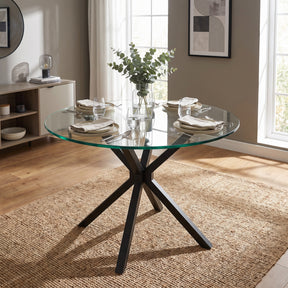 [Glass] Skyra 90cm Round Glass Dining Table set for four on a textured woven rug in a brightly lit room.