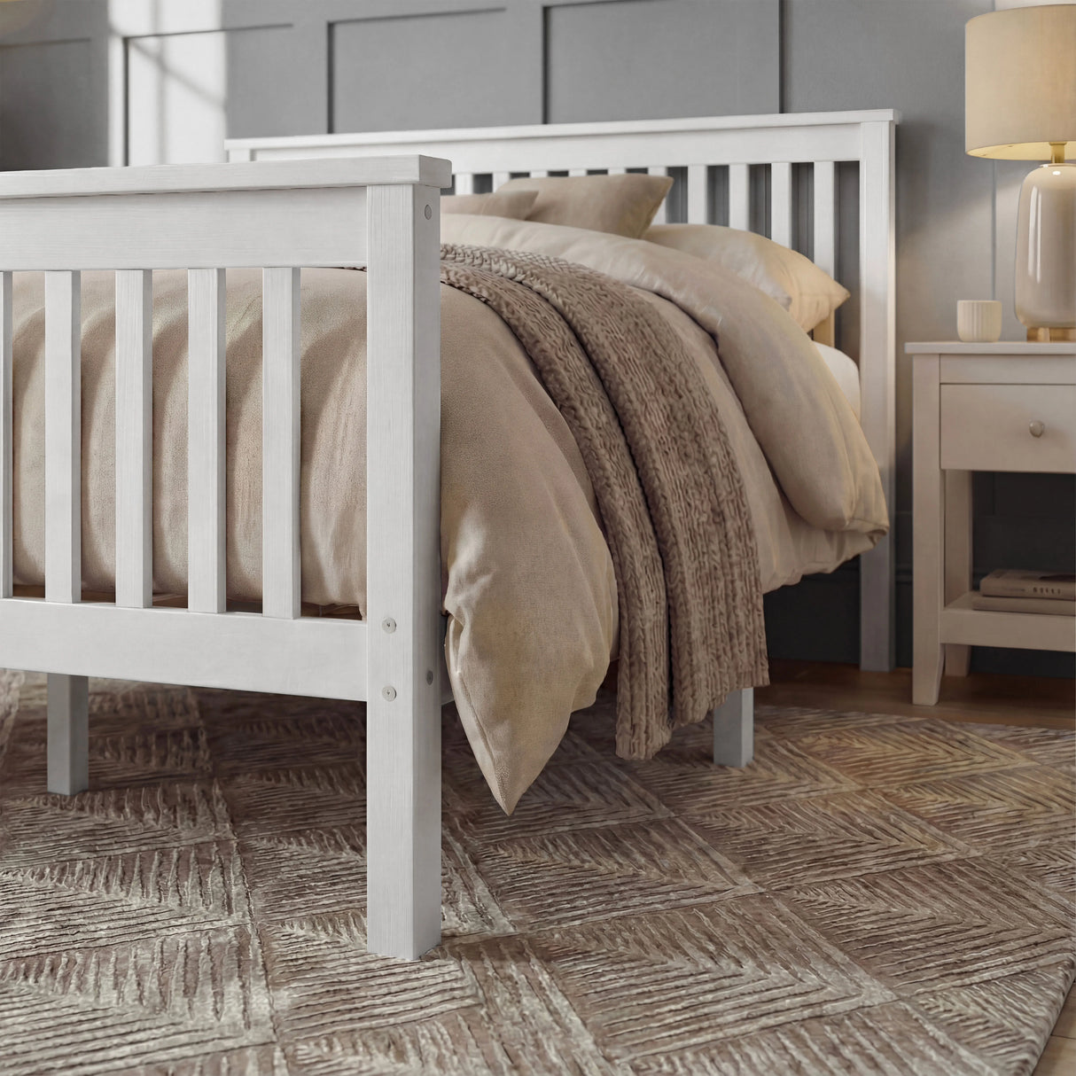 White wooden double bed frame with slatted pattern, neutral bedding, placed in a softly styled bedroom