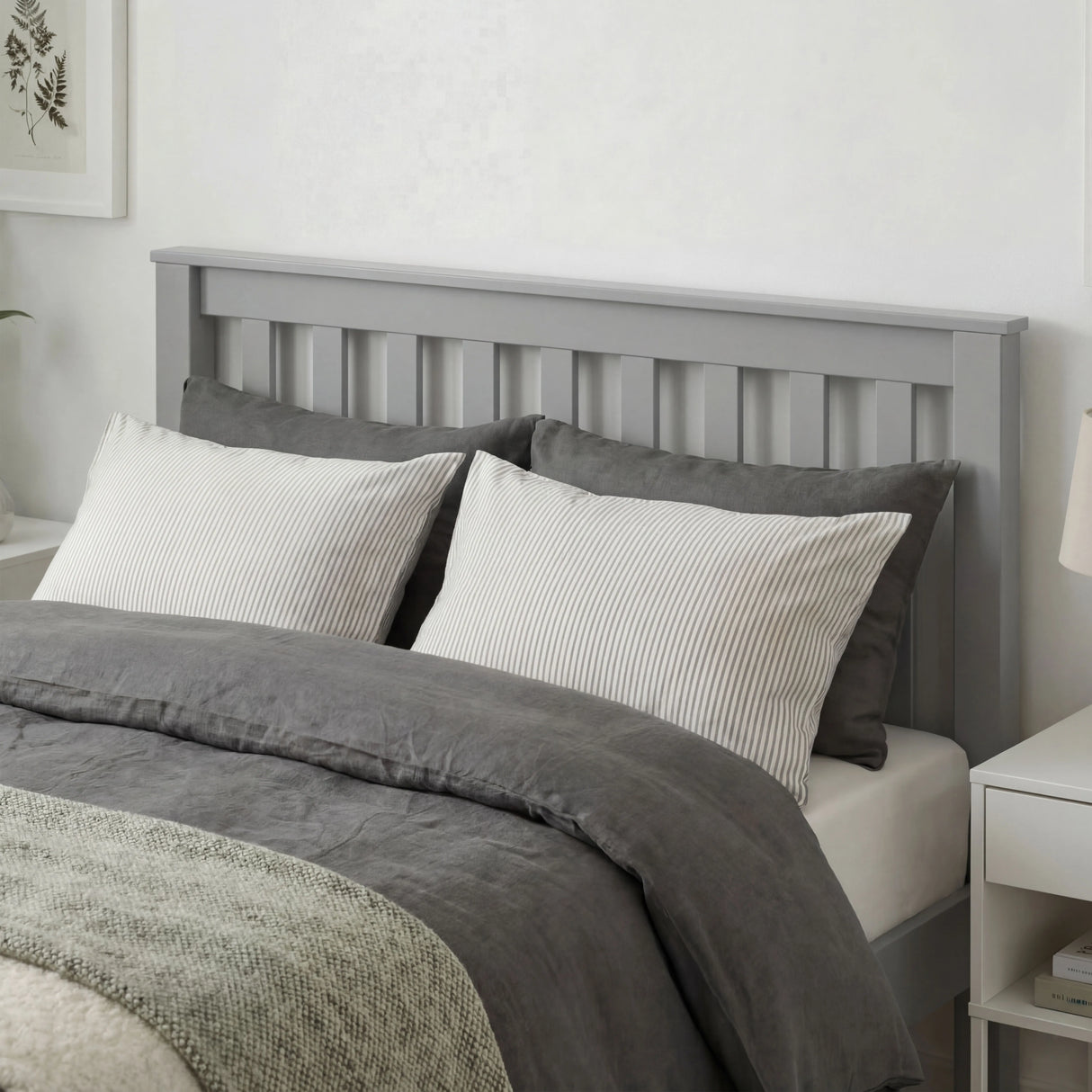 Grey wooden single bed frame with slatted headboard, soft bedding, and a minimalist bedroom design